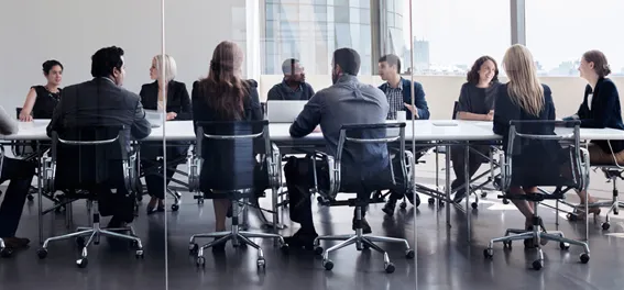 Mehrere Personen sitzen an einem großen Konferenztisch in einem modernen Besprechungsraum.